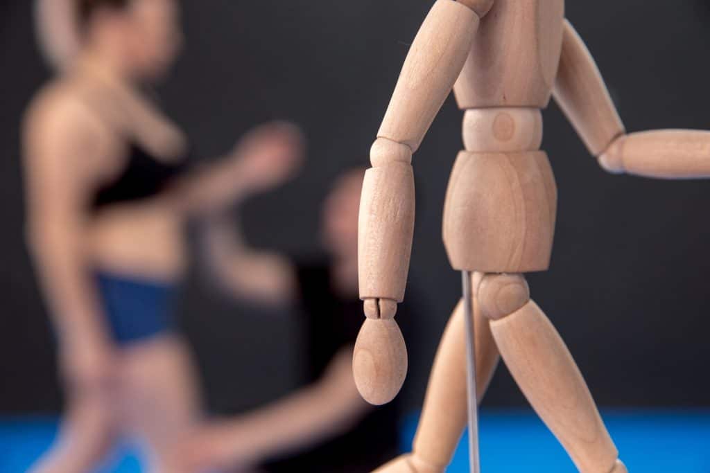 Good posture vs bad posture. Person assisting someone with their posture, with a wooden figure of a person