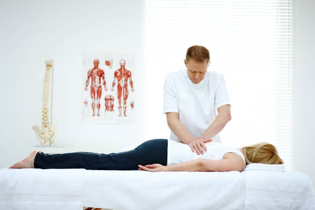 Male osteopath treating back problem of a woman